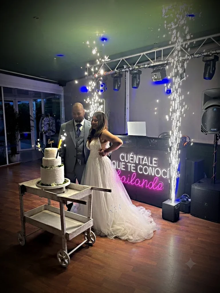 Los novios cortando la tarta entre chispas frías junto a la cabina de Sonoralia Experience
